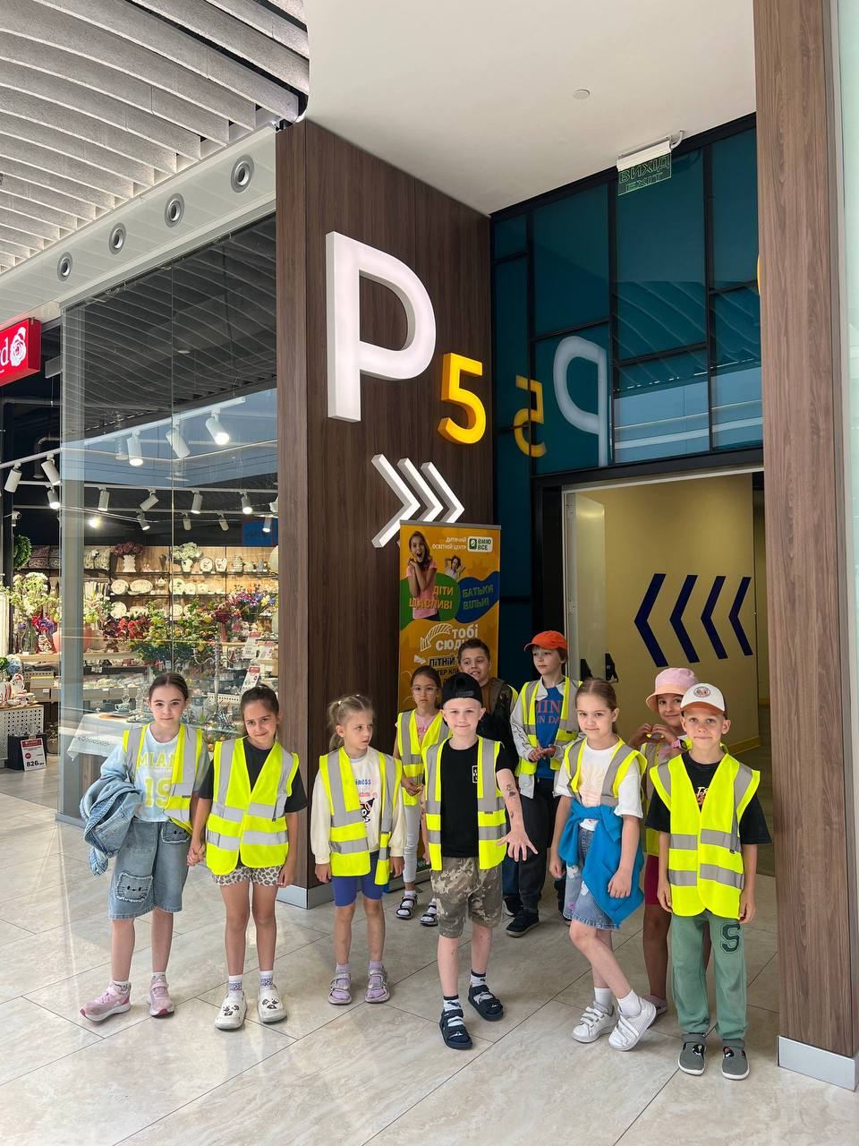 Група дітей у сигнальних жилетах біля входу P5 у River Mall